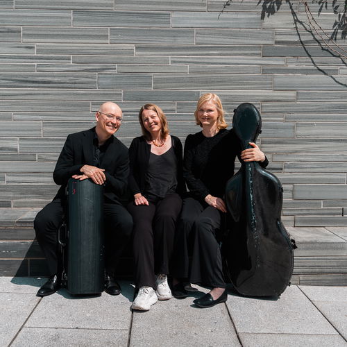 Tre musikere sitter på en steinbenk